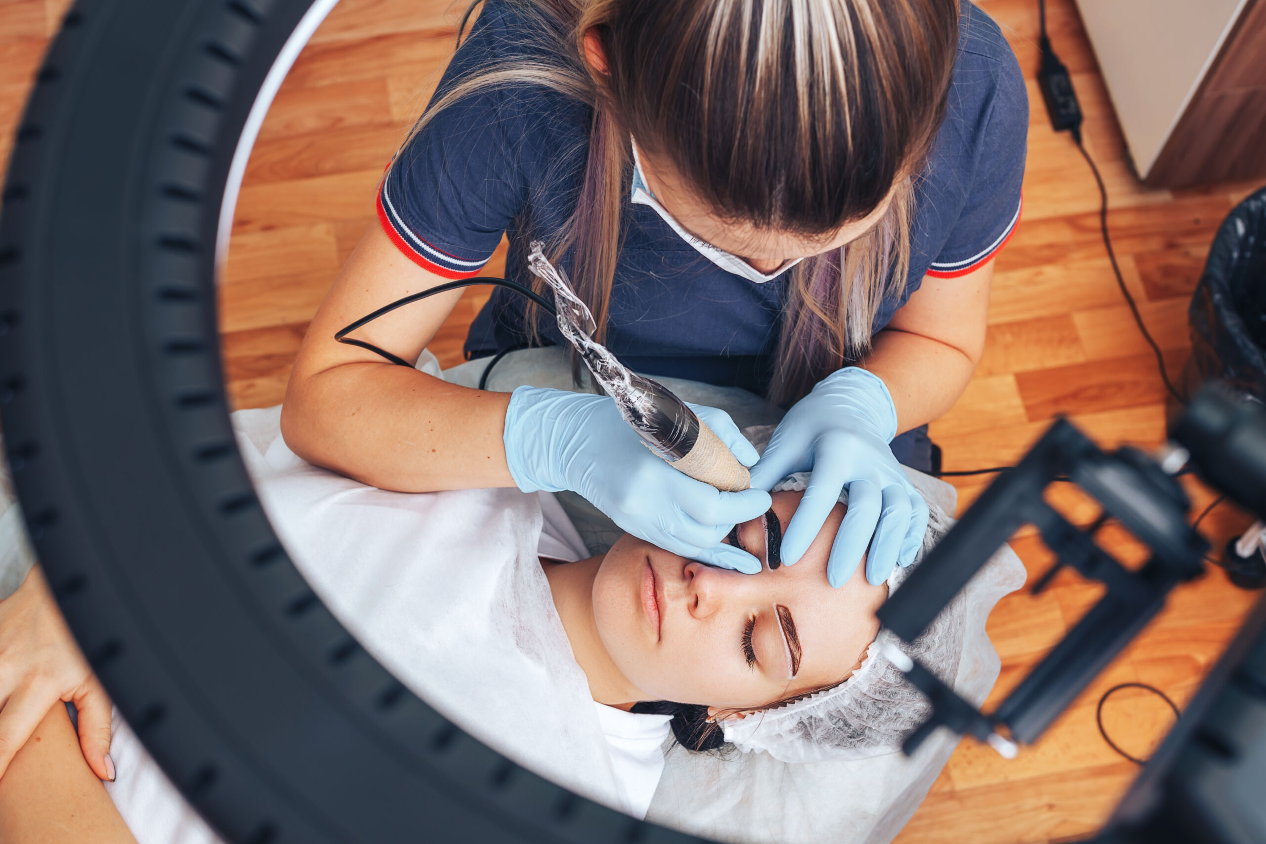 beautician making a permanent make-up procedure on eyebrows using a machine